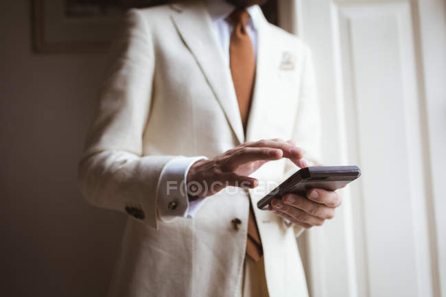 Средняя часть жениха использует свой мобильный телефон дома — стоковое фото
