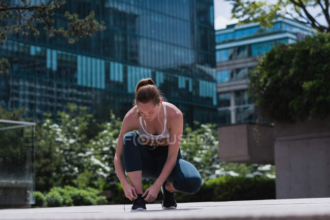 Jovem mulher desportiva amarrando atacadores de sapatos — Fotografia de Stock