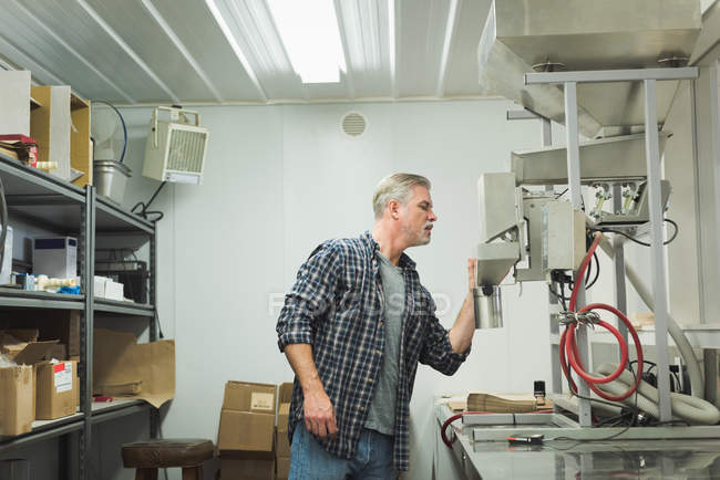 Uomo che controlla la macchina della raffineria di grano in fabbrica — Foto stock