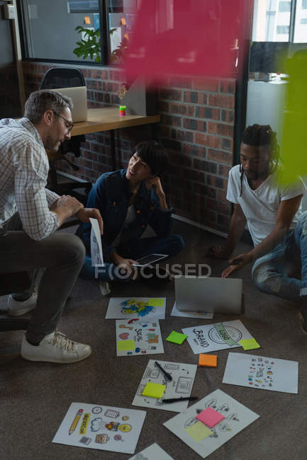 Business colleagues discussing over documents on floor in office. — Stock Photo