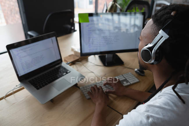 Ejecutiva masculina con auriculares trabajando en el escritorio en la oficina
. - foto de stock