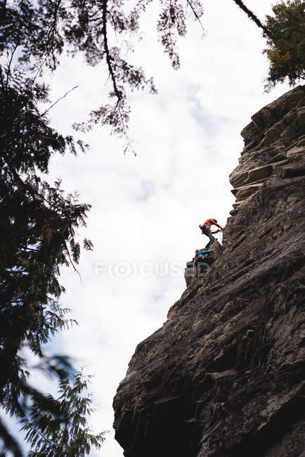 Низький кут зору скелелаз сходження кам'янистій скелі — стокове фото