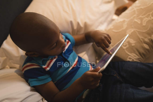 Високий кут зору хлопчика, який грає з цифровим планшетом у спальні . — стокове фото