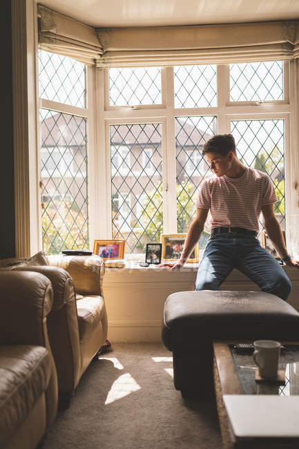 Mann sitzt zu Hause im Sonnenlicht auf Fensterbank. — Stockfoto