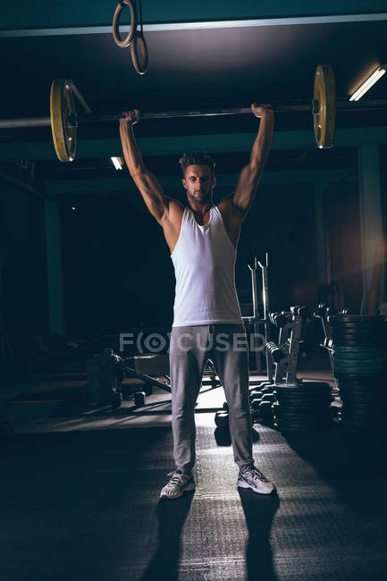 Portrait d'homme musclé faisant de l'exercice avec haltère dans la salle de fitness — Photo de stock