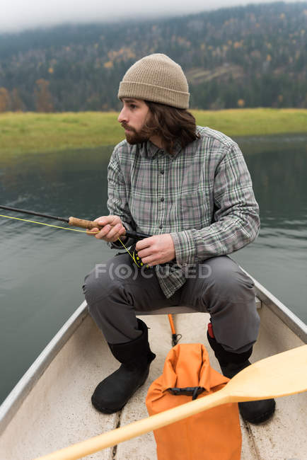 Pêcheur avec pêche monté sur un bateau par une journée brumeuse — Photo de stock