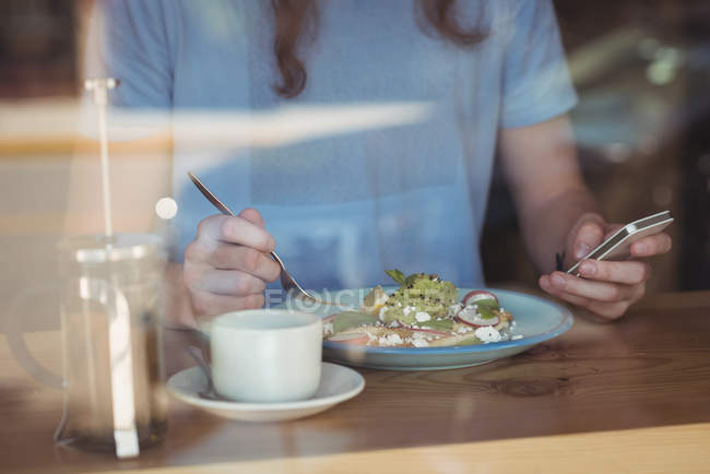 Середина чоловіка, який користується мобільним телефоном під час сніданку в кафе — стокове фото