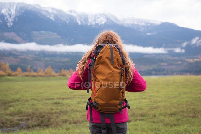 Vista trasera de Mujer con mochila mirando montañas cubiertas de nieve - foto de stock