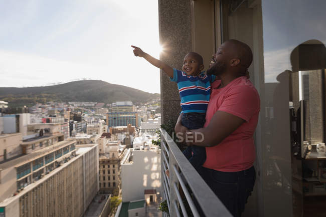 Padre che porta il figlio che punta in balcone a casa . — Foto stock