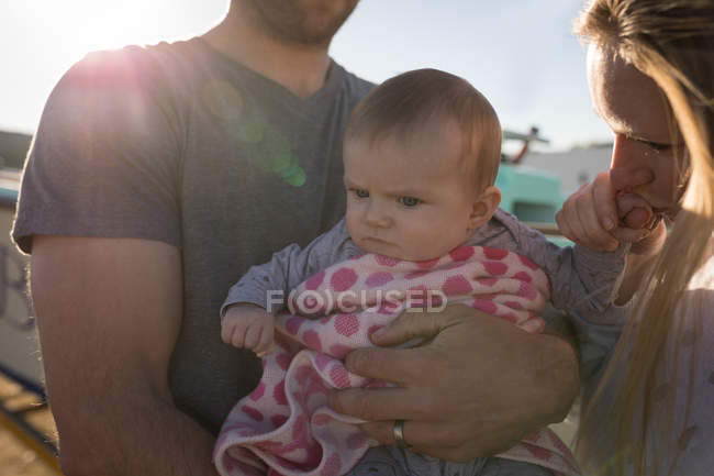 Parents holding baby boy at backyard in sunlight. — Stock Photo