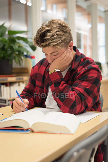 Teenage boy studying in library at university — Stock Photo