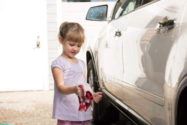 Mädchen wäscht an einem sonnigen Tag ein Auto in der Garage — Stockfoto