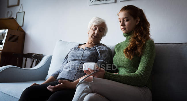 Abuela y nieta mirando auriculares de realidad virtual en la sala de estar en casa - foto de stock