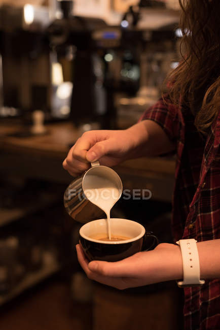 Sección media de barista femenina preparando café en el mostrador en la cafetería - foto de stock