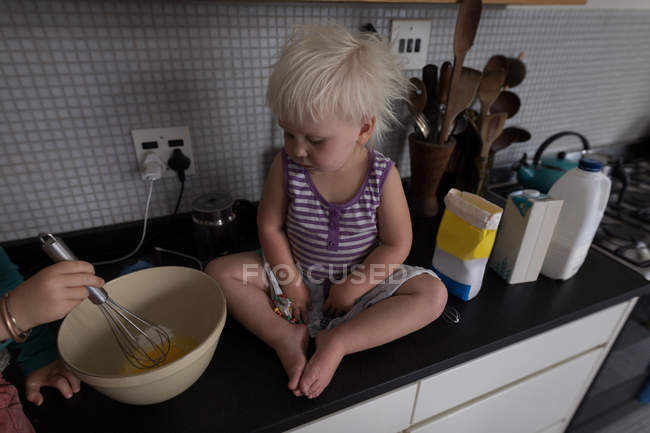 Bambino ragazza guardando come fratello preparare il cibo in cucina a casa . — Foto stock