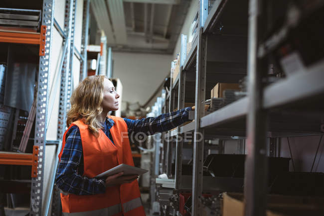 Female worker maintaining record on digital tablet at factory warehouse — Stock Photo