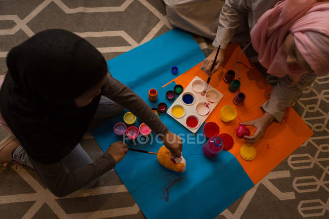 Musulmana chica y su madre haciendo acuarela pintura en casa - foto de stock
