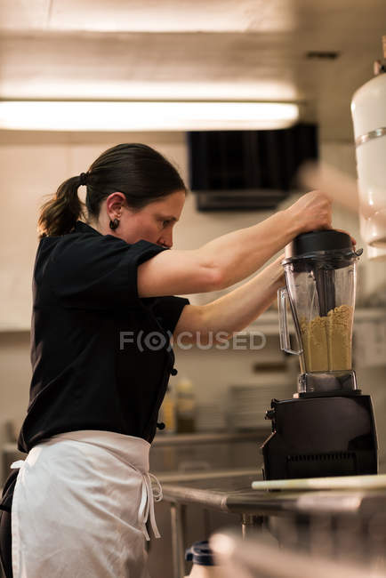 Close-up de chef usando um moedor em uma cozinha comercial — Fotografia de Stock