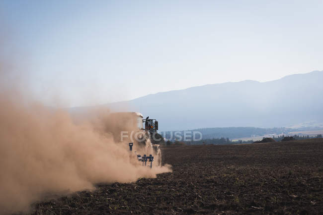 Трактор підкидає поле на сонячний день — стокове фото