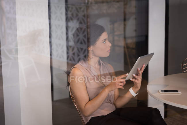Ejecutiva de oficina femenina usando tableta digital en cafetería en oficina creativa - foto de stock