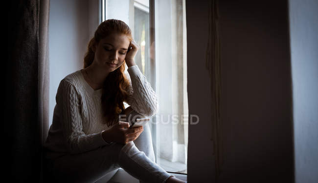 Pensativo adolescente utilizando el teléfono móvil en casa - foto de stock