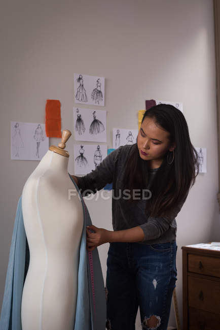 Diseñador de moda que mide la tela en el maniquí en el estudio de diseño . - foto de stock