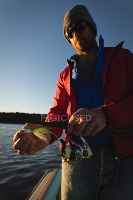 Man tying bait in fishing rod on motorboat. — Stock Photo