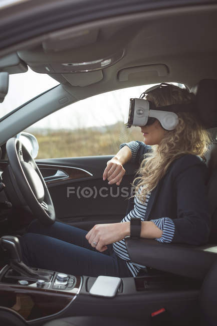 Side view of female executive using virtual reality headset in a car — Stock Photo