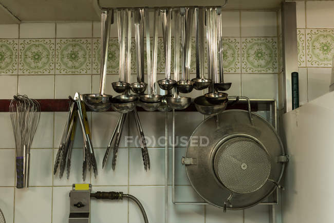 Primer plano de cucharón, tanga, batidor y colador en la cocina - foto de stock