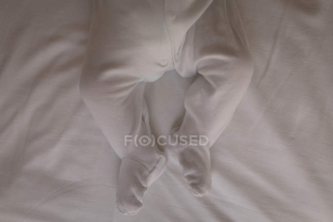 Close-up of baby in baby footie lying on bed at home — Stock Photo