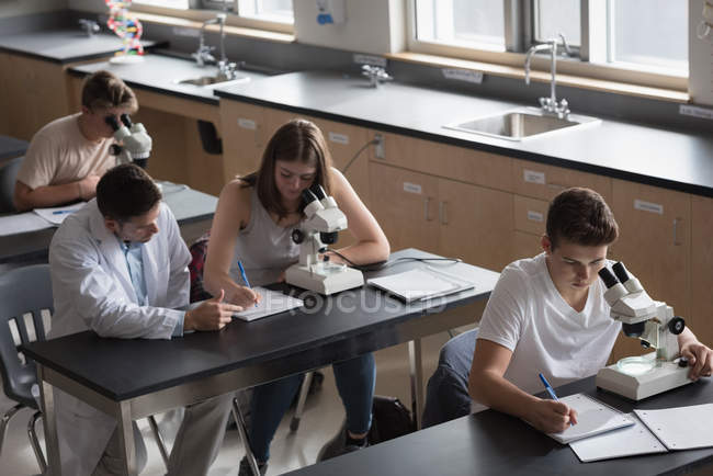 Учитель помогает студентам в экспериментах в лаборатории — стоковое фото