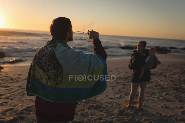 Familie spielt bei Sonnenuntergang am Strand — Stockfoto