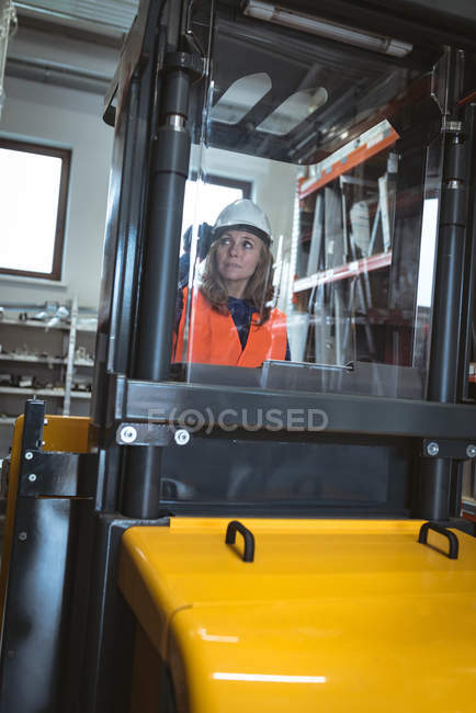 Female worker driving forklift in warehouse — Stock Photo
