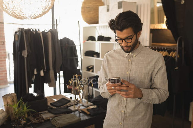 Hombre usando el teléfono móvil en la tienda boutique - foto de stock