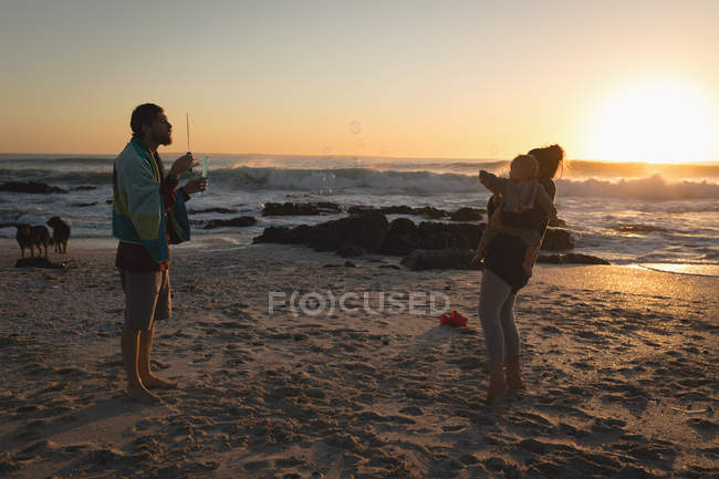 Familie spielt bei Sonnenuntergang am Strand — Stockfoto