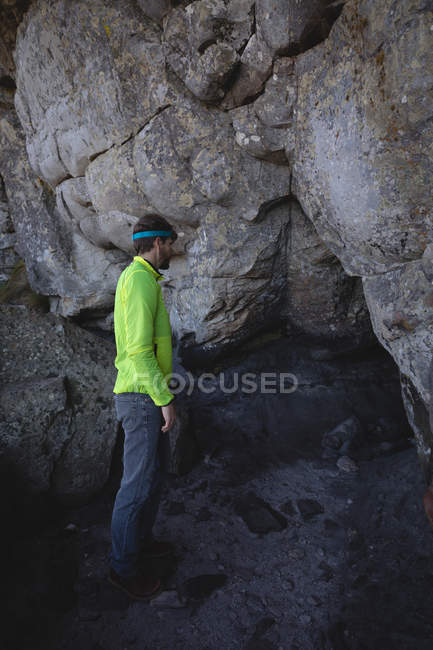 Вид збоку на пішохода, що стоїть біля входу в печеру — стокове фото