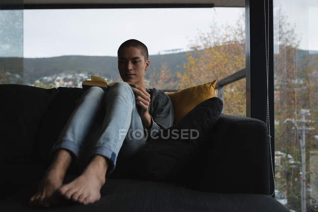 Молода людина, читаючи книгу в вітальня в домашніх умовах — стокове фото