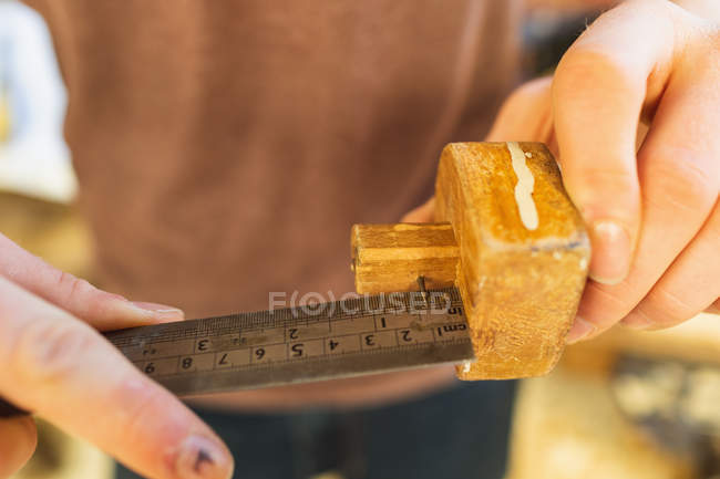 Mid section of male carpenter measuring marking gauge with ruler in workshop — Stock Photo