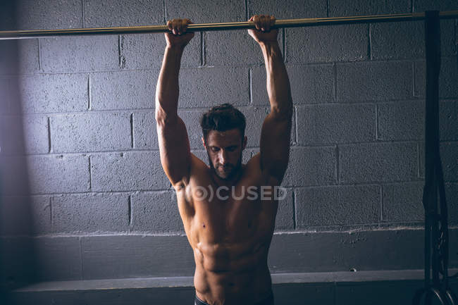 Muskulöser Mann beim Training an der Klimmzugstange im Fitnessstudio — Stockfoto