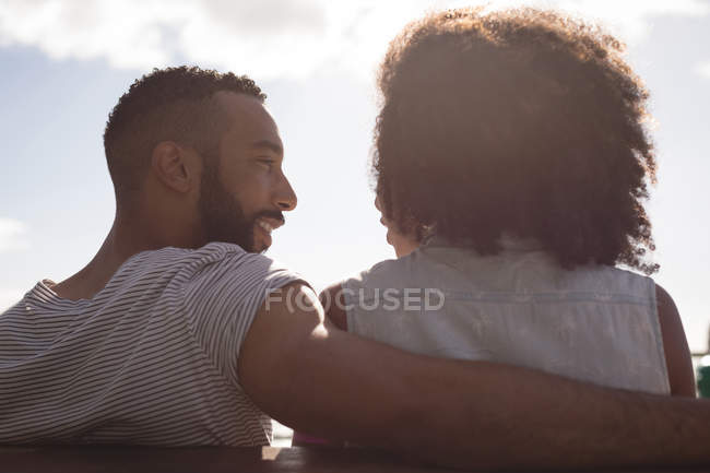 Glückliches Paar interagiert miteinander, während es auf Bank sitzt — Stockfoto