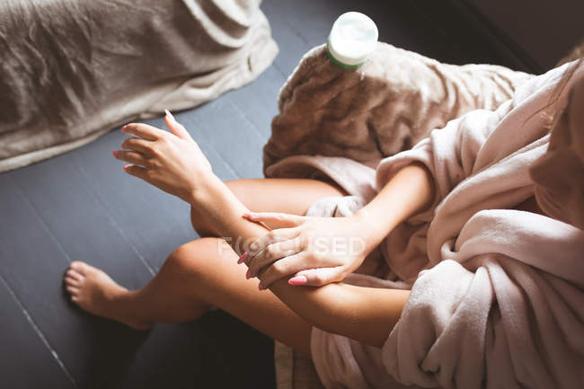 Femme appliquant de la crème sur le corps dans la chambre à coucher à la maison . — Photo de stock