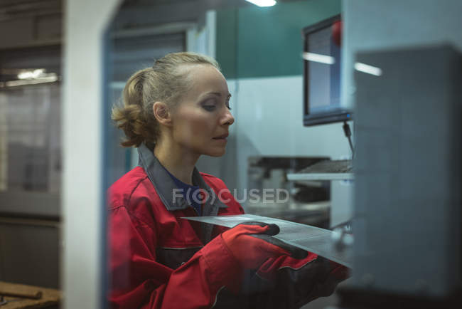 Trabalhadora verificando uma placa de máquina na fábrica — Fotografia de Stock