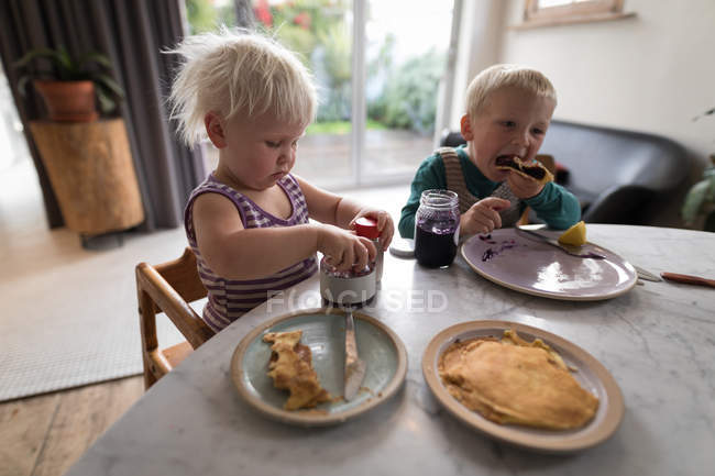 Kids having pancakes as breakfast in living room at home. — Stock Photo