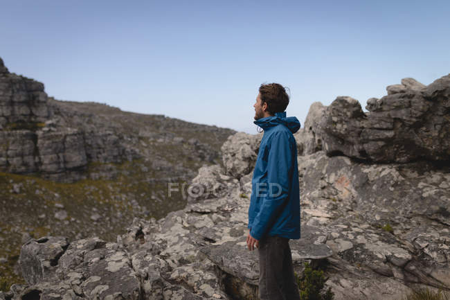 Vista lateral del excursionista de pie en la montaña rocosa - foto de stock