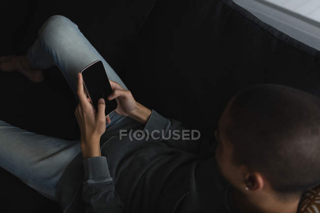Jeune homme utilisant un téléphone portable dans le salon à la maison — Photo de stock