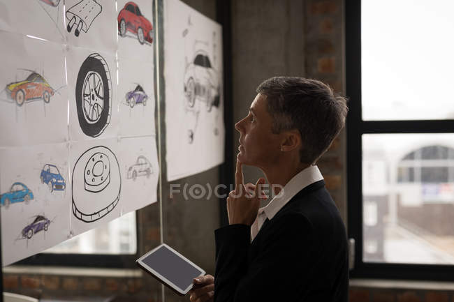 Imprenditrice guardando grafico e schizzi in ufficio . — Foto stock