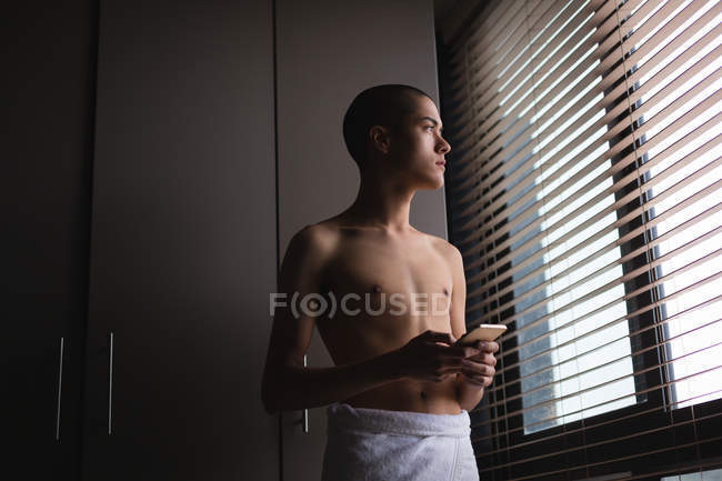 Thoughtful young man using mobile phone at home — Stock Photo