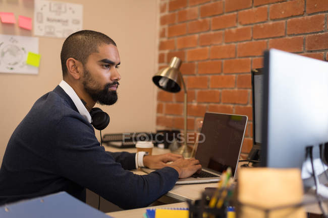 Esecutivo maschile che lavora su laptop alla scrivania in ufficio — Foto stock