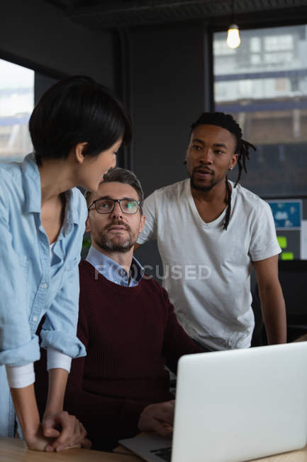 Executivos discutindo sobre laptop na mesa no escritório . — Fotografia de Stock