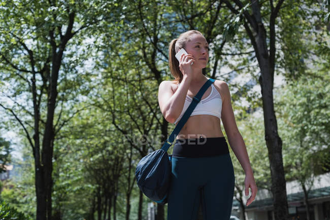Jovem mulher desportiva falando no telefone celular na rua — Fotografia de Stock